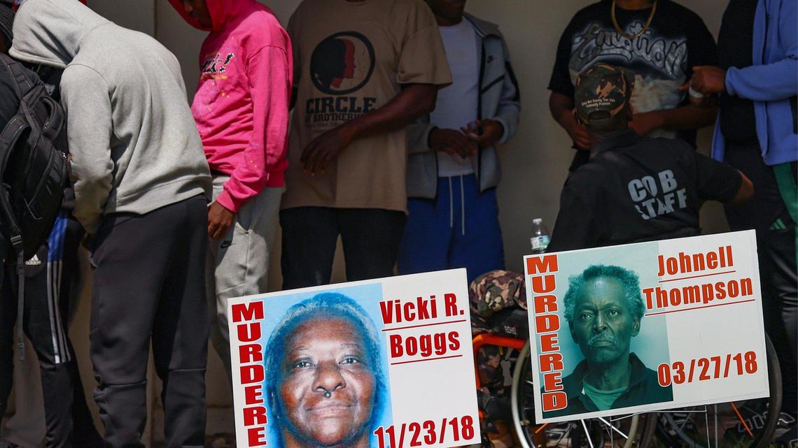 Young men gather with staff members of Circle of Brotherhood behind signs of those who were killed by gun violence at a rally to address a budget gap following the loss of federal funding. 