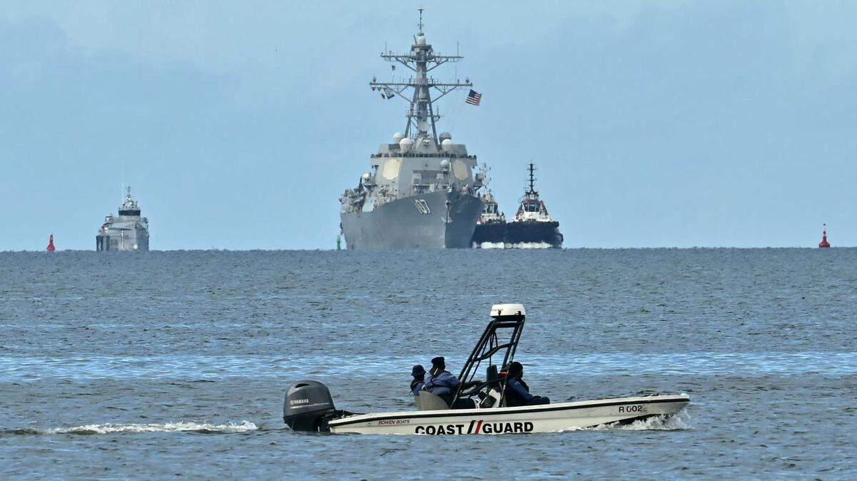 Una lancha rápida de la Guardia Costera de Trinidad y Tobago patrulla mientras el buque de guerra USS Gravely se observa a lo lejos desde Puerto España, el 26 de octubre de 2025. El navío estadounidense visitará Trinidad y Tobago para realizar ejercicios conjuntos cerca de la costa de Venezuela, en el marco de la campaña de Washington contra presuntos narcotraficantes en la región.