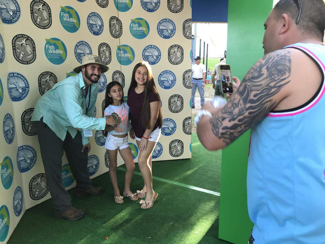 Rangel Caballero takes a picture of daughters Summer, 12, and Skye, 9, next to a baby python held by FWC conservation biologist Eric Suarez during Super Bowl Live at Bayfront Park on Jan. 25, 2020.