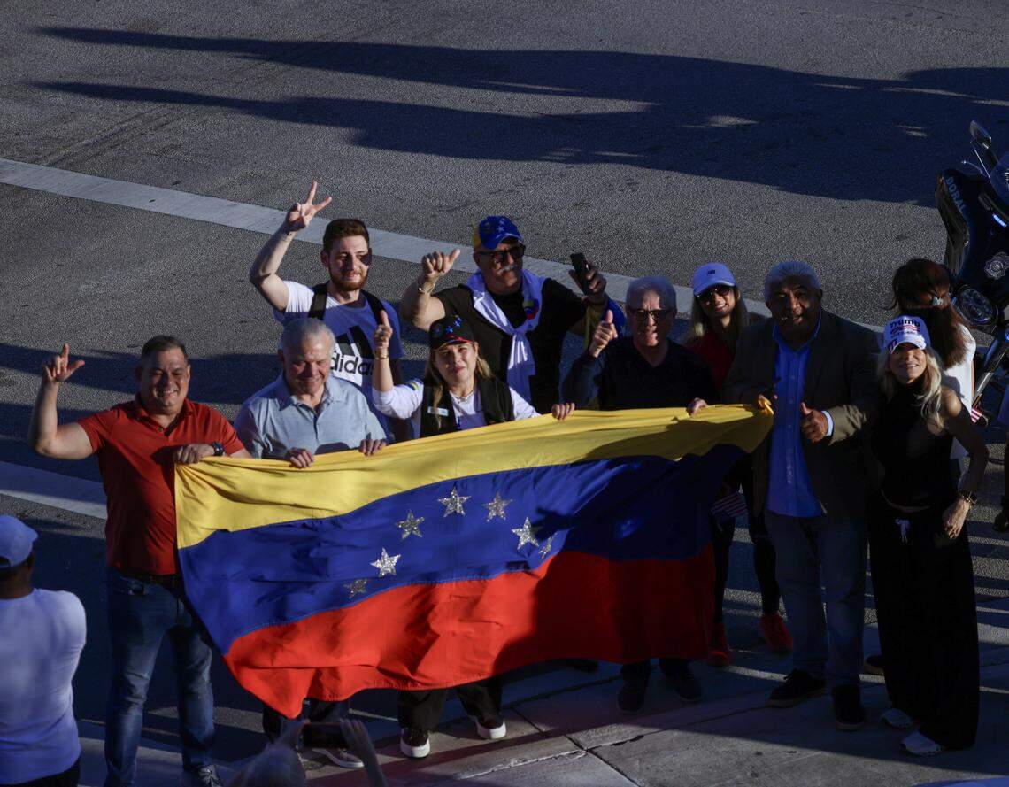 A small group of Venezuelans stretch a Venezuelan flag while waiting for President Donald Trump’s arrival as he visited El Arepazo, a Venezuelan restaurant and community hub in Doral, for a brief four-minute stop, greeting Republican guests invited to the restaurant on Monday, March 9, 2026, in Doral, Florida.