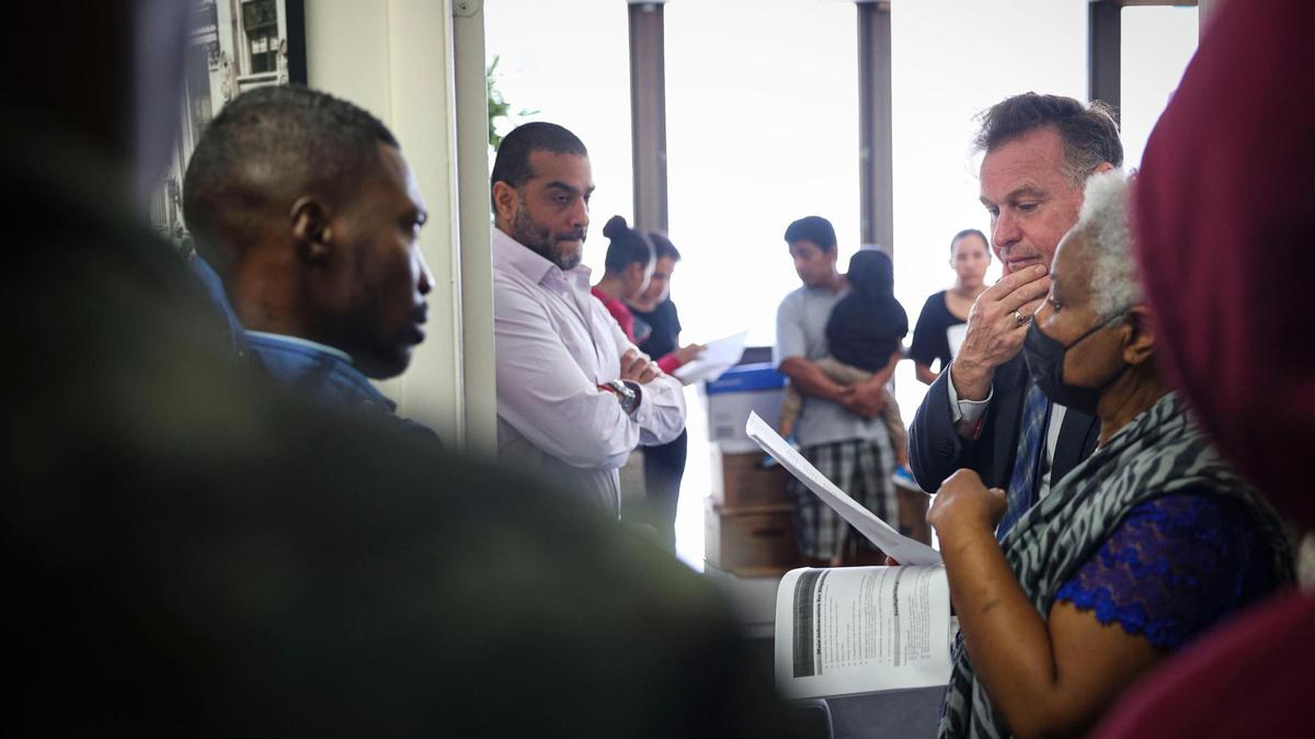 Randy McGrorty, co-founder of Catholic Legal Services, right, and Damaso Ramirez, center, try to organize migrants looking for assistance inside Catholic Charities legal services on Monday, Jan. 9, 2023, in downtown Miami.