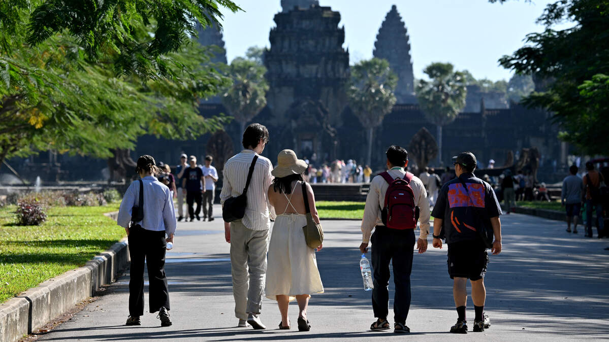 This photo taken on December 18, 2025 shows tour guide Bun Ratana (2nd R) walking with tourists in front of the Angkor Wat temple in Siem Reap province.