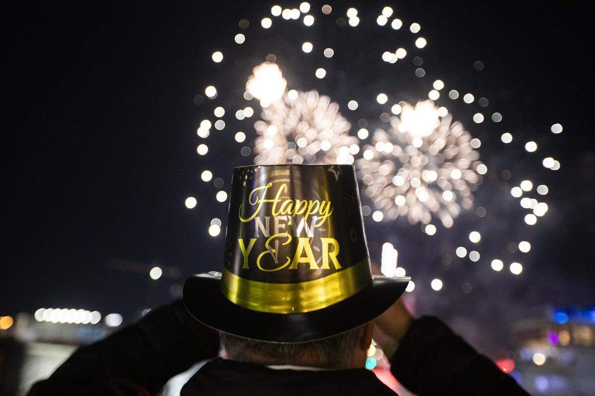 A festive partygoer watches the fireworks over Biscayne Bay during the New Year’s Eve celebration at Bayfront Park on Dec. 31, 2025, in Miami.