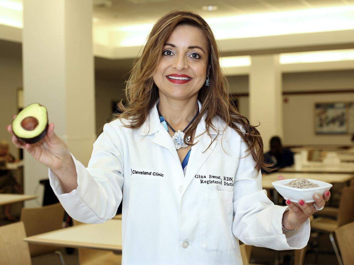 Gina Sweat, a registered dietitian at Cleveland Clinic Florida, holds an avocado and sunflower seeds — some of the healthy food choices recommended for women — in 2016 in the cafeteria at Cleveland Clinic Florida in Weston.