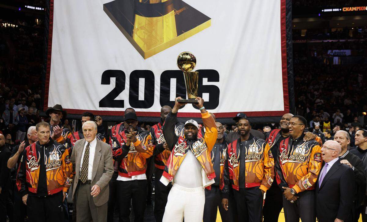 Dwayne Wade lifts the 2006 Championship trophy with the rest of the 2006 team during a Champions Night ceremony recognizing the team at halftime of a Miami Heat game on Feb. 3, 2026, at Kaseya Center in Miami.