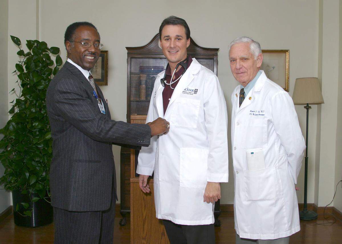 In this file photo from April 14, 2004, then-Jackson Health System CEO/Public Health Trust President Marvin O’Quinn saluted State Rep. Rene Garcia. University of Miami School of Medicine Dean Emeritus, Bernard J. Fogel, right, administered the Hippocratic Oath.