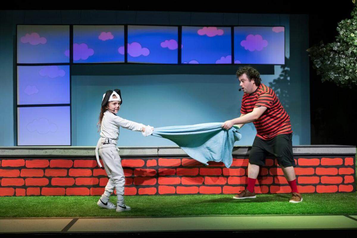 From left, Miami Children’s Museum Charter School student Ivy Rose Linares as Snoopy, playfully battles Linus, played by Pablo de Pablo, for his beloved blanket.
