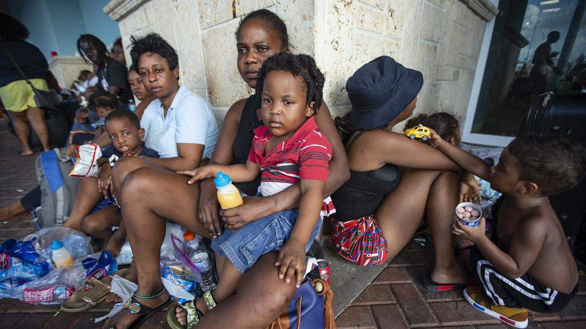 Medjeena Francois, 31, with son Zion Carvil, 2, waits with hundreds of people outside the Leonard M. Thompson International Airport in Abaco on Thursday hoping to be evacuated off the island after Hurricane Dorian hit the Bahamas. Relief flights are taking out the elderly and sick, but many say an air bridge will be required to move all of those who want to leave the hard-hit northern islands of the Bahamas.
