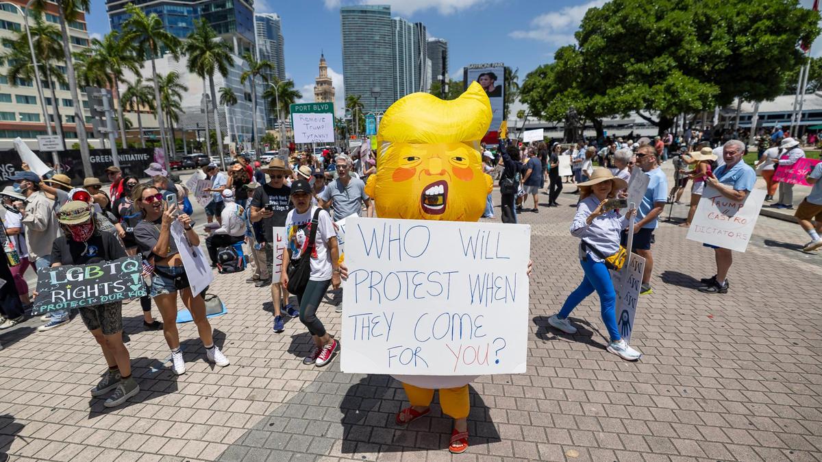 Kelly Robinson, 51, wears an inflatable costume of Donald Trump as she attends a National Day of Action protest against the president and his administration at the Torch of Friendship on Saturday, April 19, 2025, in downtown Miami, Fla.