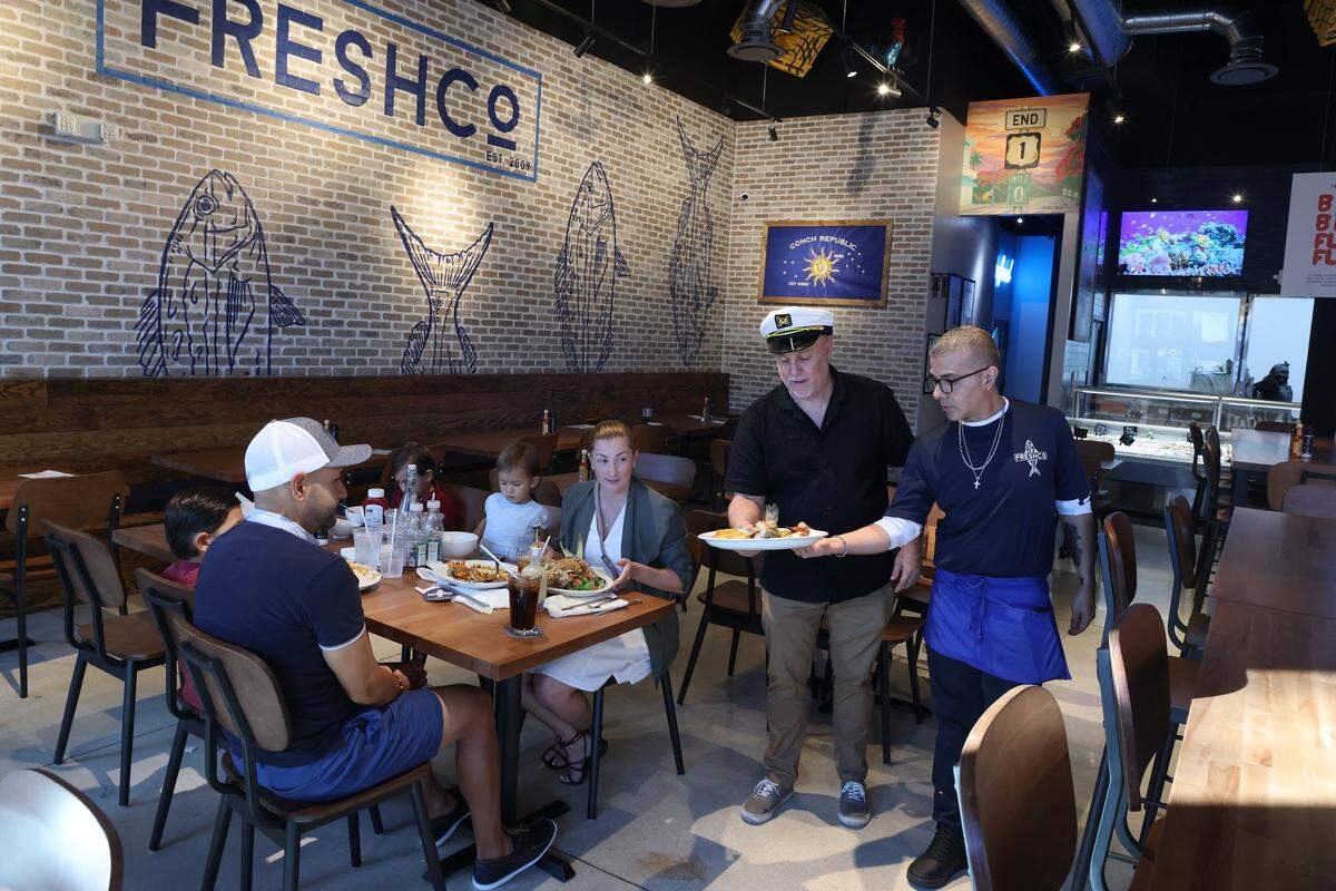 Key West native Mario Palazon, center, assist in serving diners in his new 127-seat restaurant in Doral, Florida, where fresh fish is sold on Wednesday, December 24, 2025.