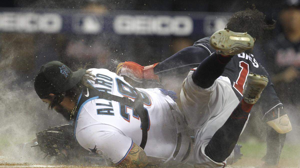 Miami Marlins catcher Jorge Alfaro (38) tags out Atlanta Braves’ Ozzie Albies (1) during the first inning of a baseball game Thursday, Aug. 8, 2019, in Miami. (AP Photo/Luis M. Alvarez)