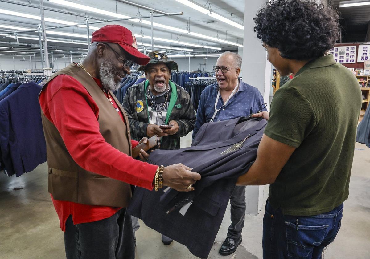 Salesman Oswaldo Chamorro, 19, at right, shows a suit to customers Tyrone Days, 75, and John Williams, 77, as they share a laugh with Kenny Sager, left to right. Days and Williams are customers at Austin Burke since the 1960’s.