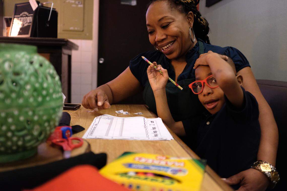 Nicole Gates helps her son, Karter, with his homework at Lil Greenhouse Grill, their family restaurant in Overtown.