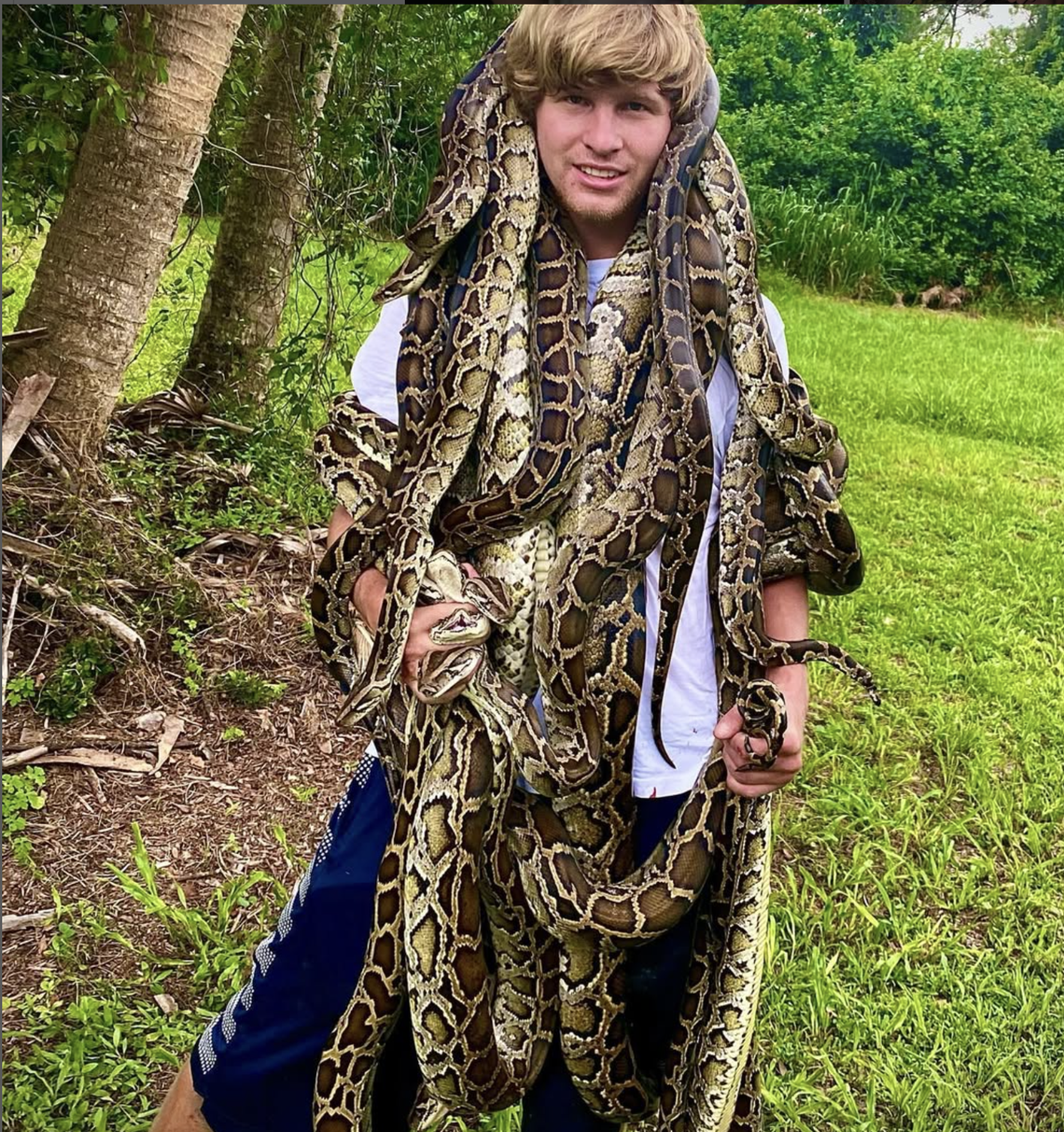 Garrett Galvin poses with invasive Burmese pythons.
