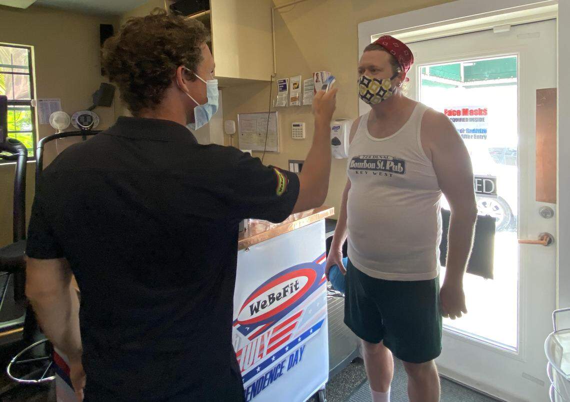 Fitness trainer Josh Carter, left, takes the tempearture of client Nathan Gay, before starting a session at WeBeFit Personal Training in Key West on May 18, 2020.