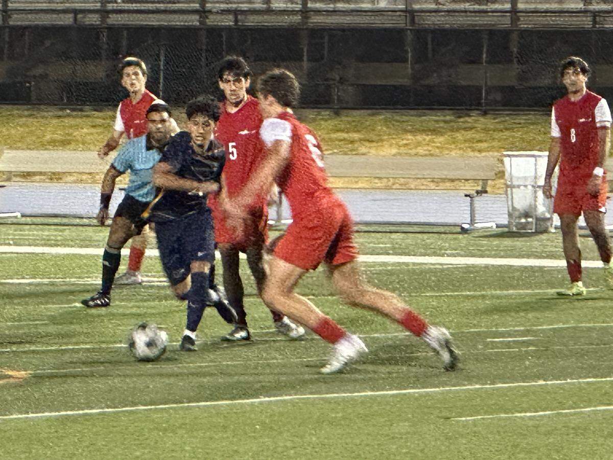 Downtown Doral’s Victor Villalobos (blue jersey) battles through MAST’s defense on Tuesday during the Dolphins’ 4-0 win over the Makos in a Region 4-3A semifinal at Tropical Park.