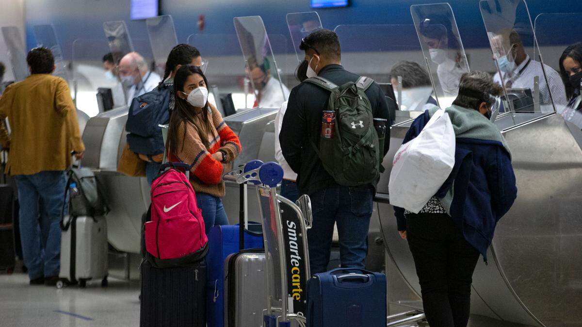 Travelers wearing protective face masks check-in their bags at the Miami International Airport on Monday, December 28, 2020 in Miami, Florida.