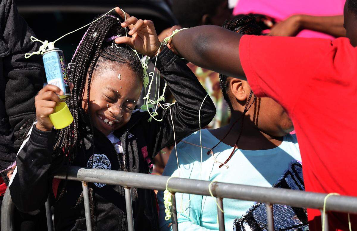 A young girl gets showered with “silly string” during the Martin Luther King Jr. Day Parade in Liberty City on Monday, Jan. 21, 2018, in Miami. 