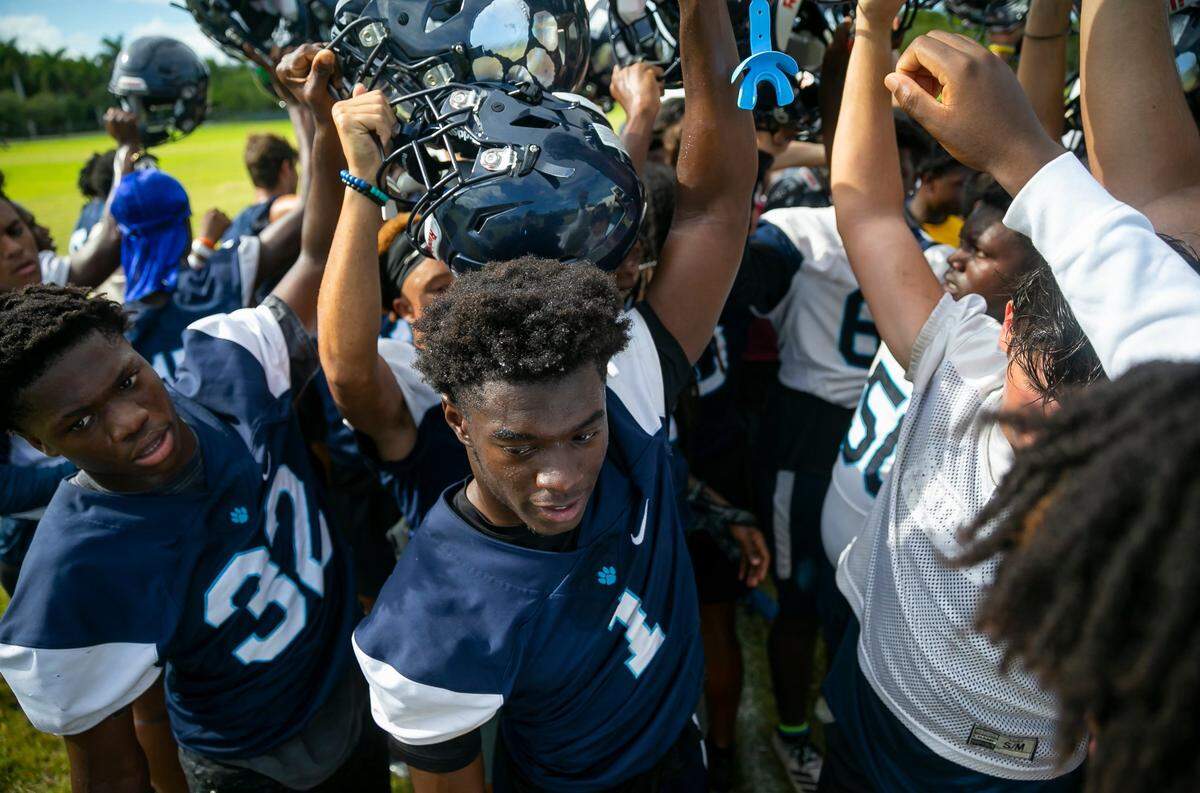 Miami Palmetto Senior High cornerback Dwight Bootle, center, huddles with his teammates at the conclusion of a preseason practice at his schools football field on Friday, Aug. 12, 2022, in Pinecrest, Fla.