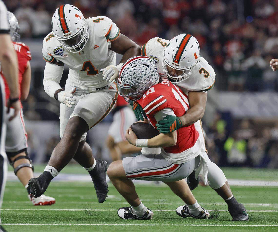 Miami Hurricanes defensive lineman Rueben Bain Jr. (4) and defensive lineman Akheem Mesidor (3) sack Ohio State Buckeyes quarterback Julian Sayin (10) during the first half of the College Football Playoff quarterfinal game in the Cotton Bowl at AT&T Stadium in Arlington, Texas on Wednesday, December 31, 2025.