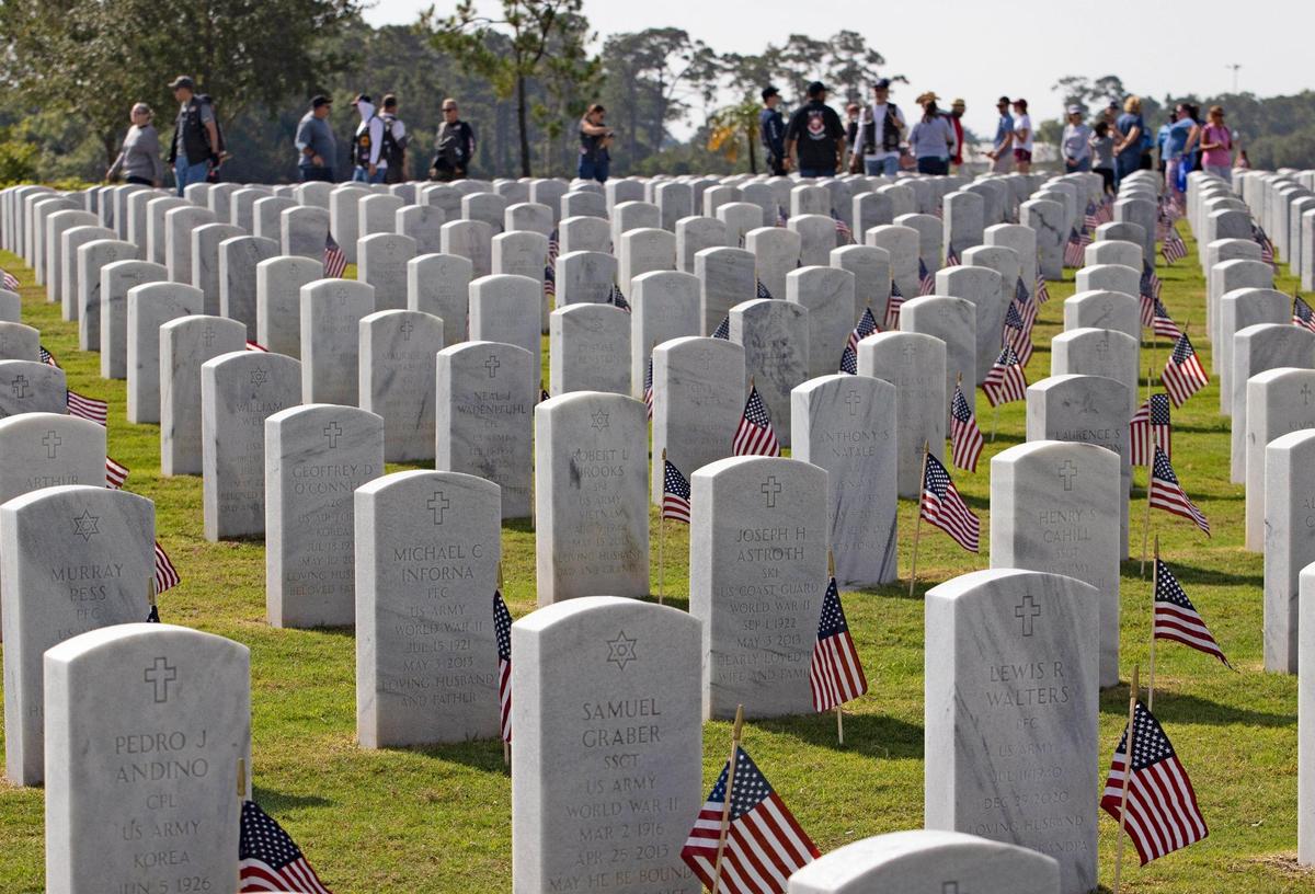 Volunteers placed American flags at the gravestones inside the South Florida National Cemetery on Sunday in preparation for a Memorial Day ceremony on Monday.