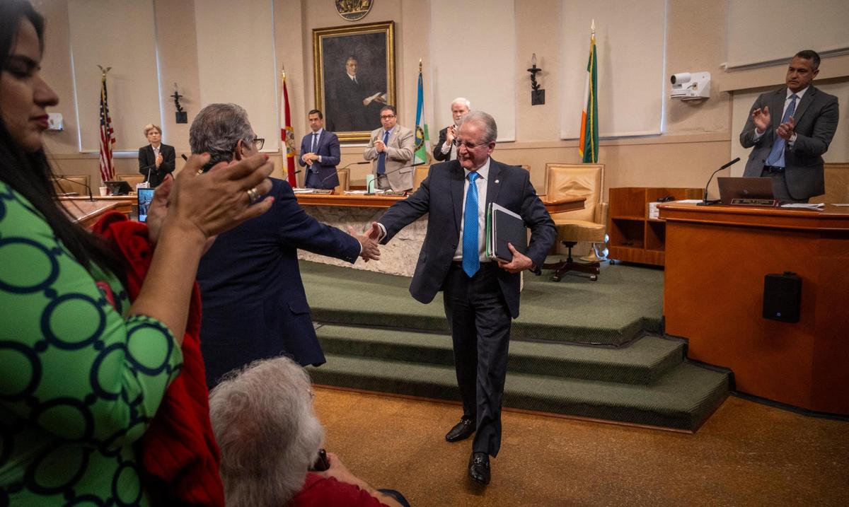 Coral Gables City Manager Peter Iglesias, center, reaches out to shake Assistant City Manager Alberto Parjus’ hand as he walks out of the Coral Gables Commission Chambers after being fired by a 3-2 vote on Feb. 13, 2024. Iglesias was rehired in 2025.