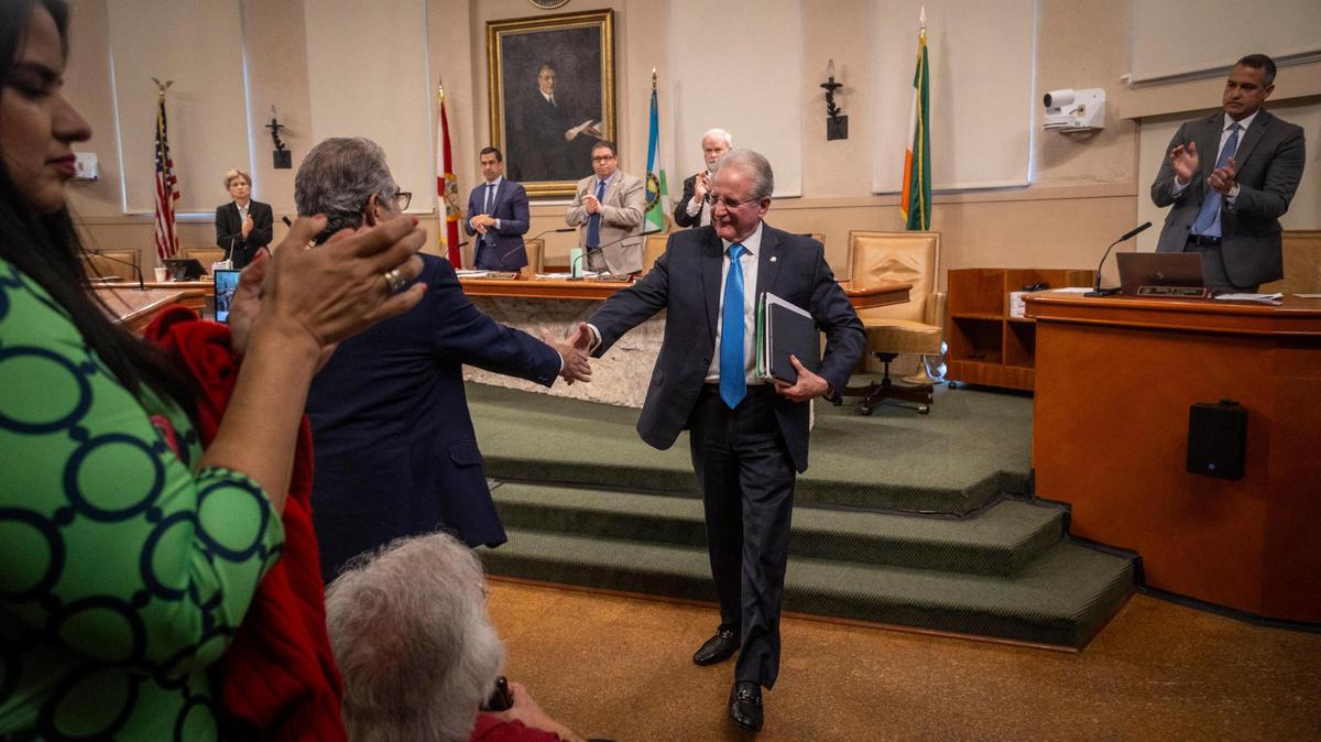 Coral Gables City Manager Peter Iglesias, center, reaches out to shake Assistant City Manager Alberto Parjus’ hand as he walks out of the Coral Gables Commission chambers after being fired by a 3-2 vote on Feb. 13, 2024. Parjus will be taking over as acting city manager until a replacement is found.
