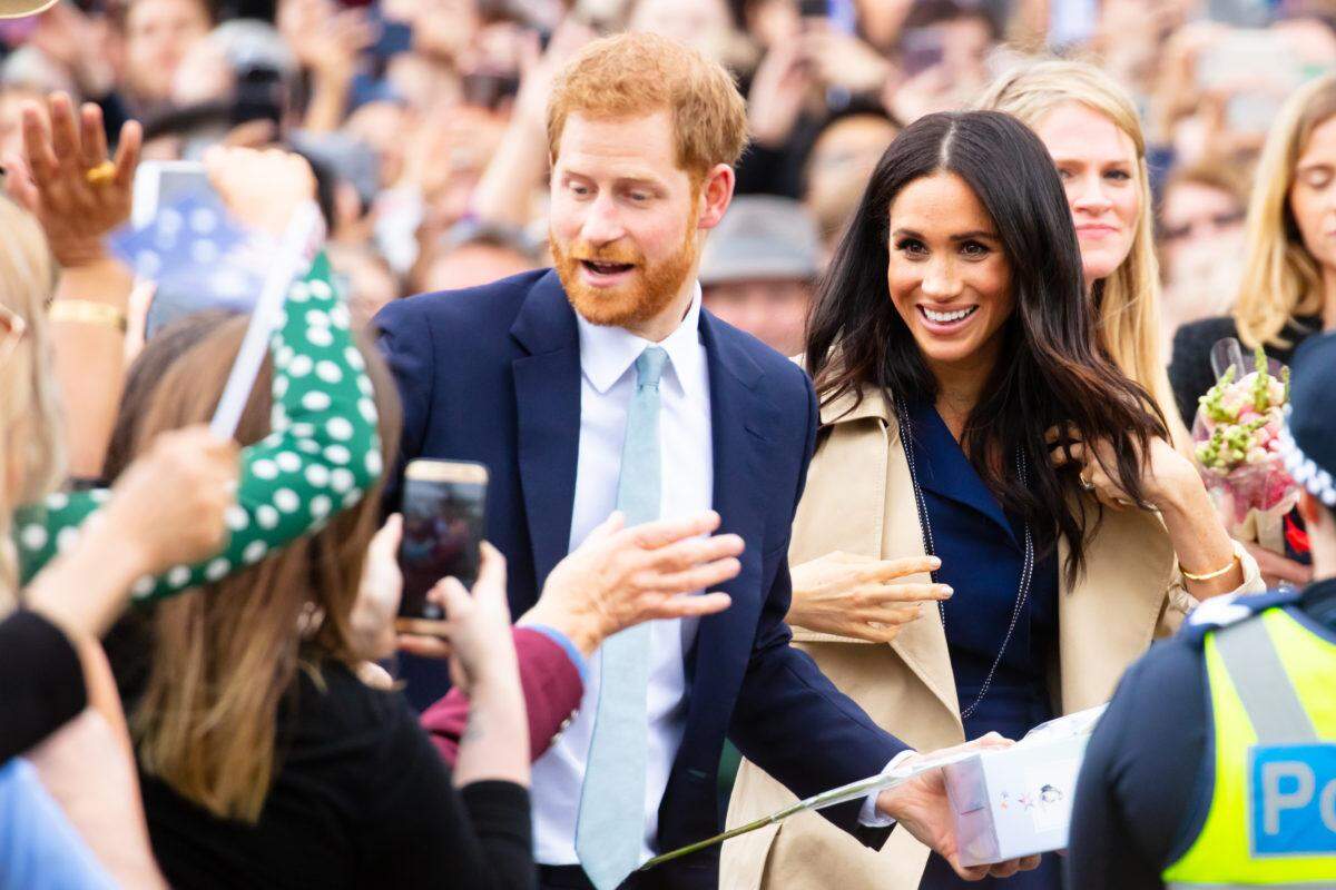 Prince Harry and Meghan Markle greeting people.