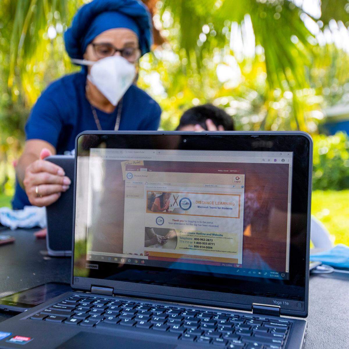 A Miami-Dade County Public Schools employee assists a migrant student with virtual learning during the coronavirus pandemic in South Florida on Thursday, May 21, 2020.