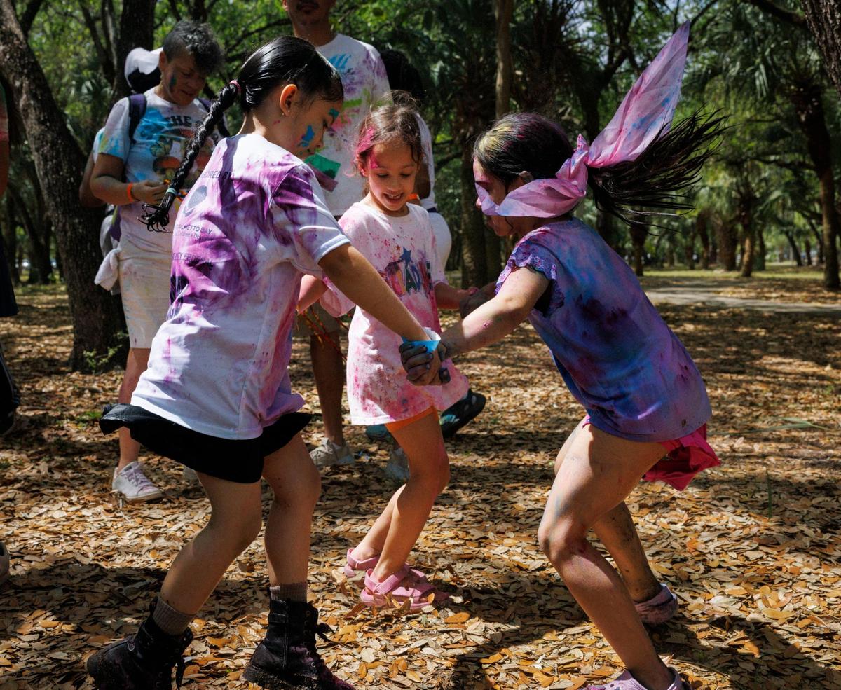 Three girls dance in a circle to the Dhol drums during the celebration of Holi, the Hindu festival of colors, on Sunday, March 16, 2025, at Kendall Indian Hammocks Park in Miami, Fla.