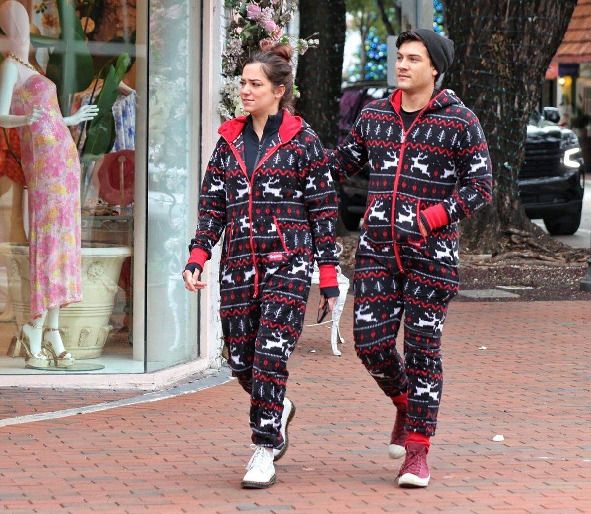 Devin Robbins, along her fiancé Devin Braddock, right, walk together in step in their matching Christmas inspired onesies. Coconut Grove residents and visitors strolled through the Center Grove wearing coats, Holiday onesies, and hoodies as temperatures drop to the 40’s likely being coldest Christmas Day in recent memory on Sunday, December 25, 2022.
