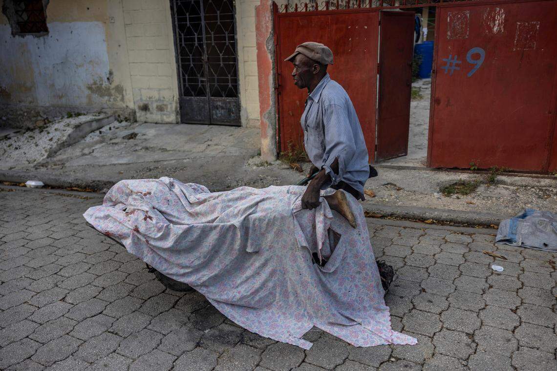 A man wheels away the body of a civilian killed in the crossfire during a gun battle between gangs and police in the Bel Air neighborhood. They are going to the morgue.