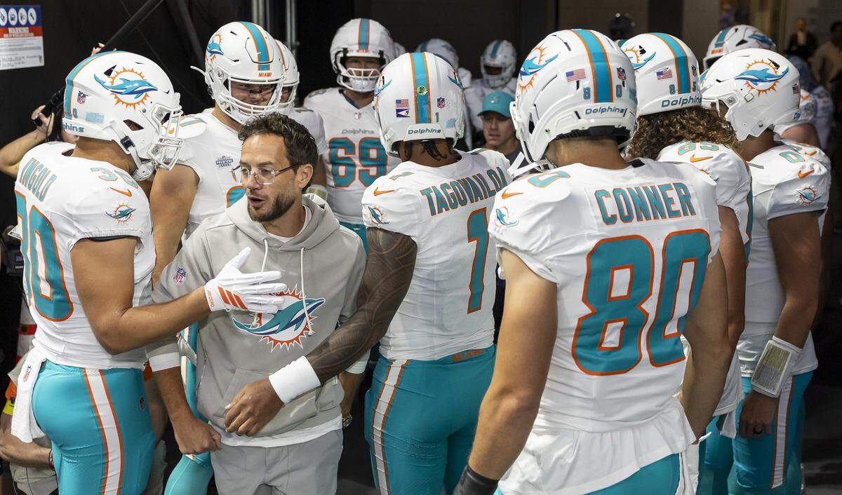 Miami Dolphins head coach Mike McDaniel walks past players as they huddle before their NFL game against the Atlanta Falcons at Mercedes-Benz Stadium on Sunday, Oct. 26, 2025, in Atlanta, Ga.