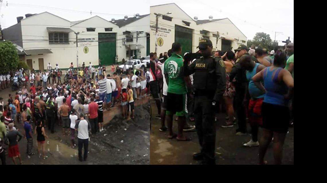 Migrantes y policías a las afueras del albergue donde se encuentran cientos de cubanos varados en Turbo, Colombia.