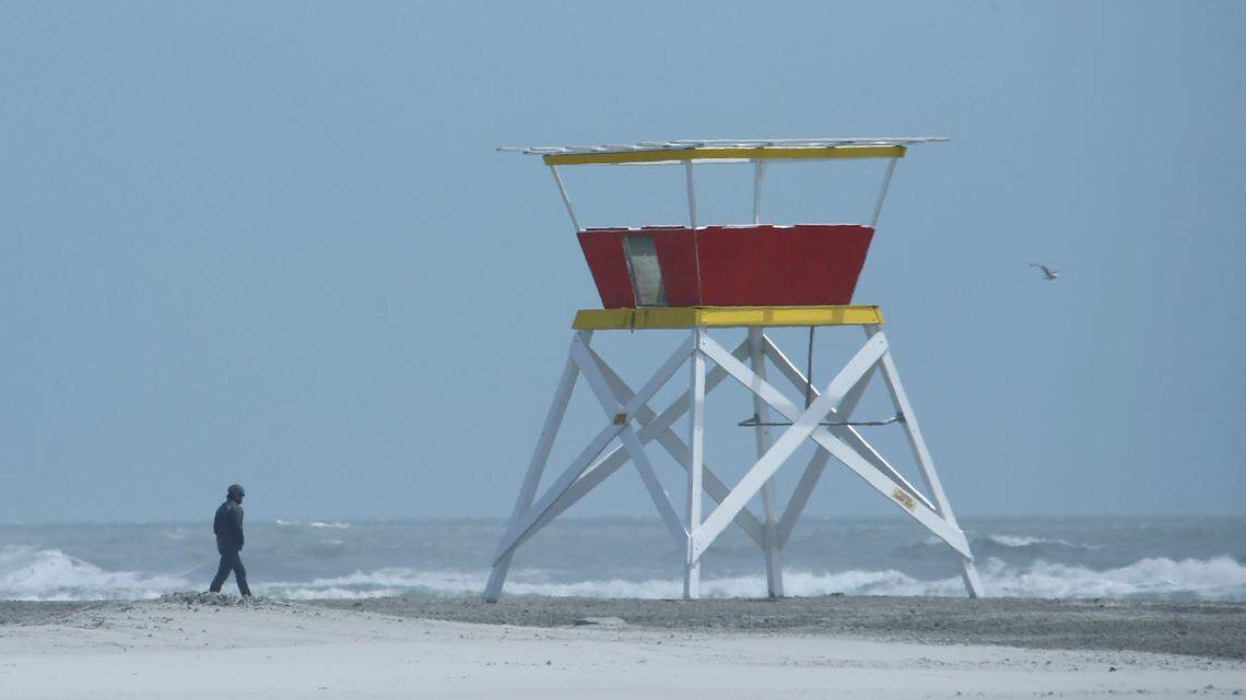 A man passes an empty lifeguard tower along the beach on May 21, 2020, in Wildwood, N.J.