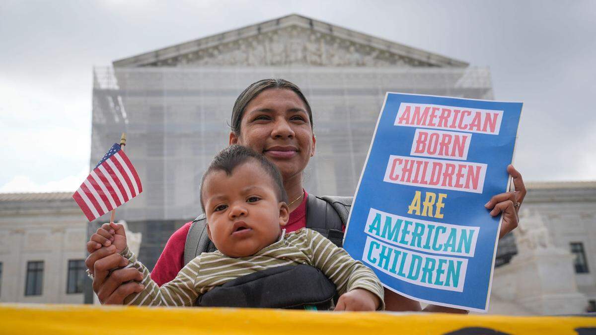 Olga Urbina and her child Ares Webster from Baltimore, MD, demonstrate outside the Supreme Court before justices hears oral arguments in Trump v. CASA, Inc. At issue in the case is if the Supreme Court should stay the district courts’ nationwide preliminary injunctions on the Trump administration’s executive order ending birthright citizenship.