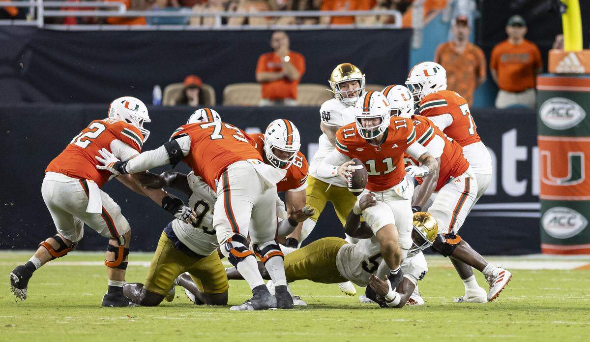 Miami Hurricanes quarterback Carson Beck (11) runs with the ball as Notre Dame Fighting Irish defensive lineman Boubacar Traore (5) defends in the second half of their NCAA football game at Hard Rock Stadium on Sunday, Aug. 31, 2025, in Miami Gardens, Fla.