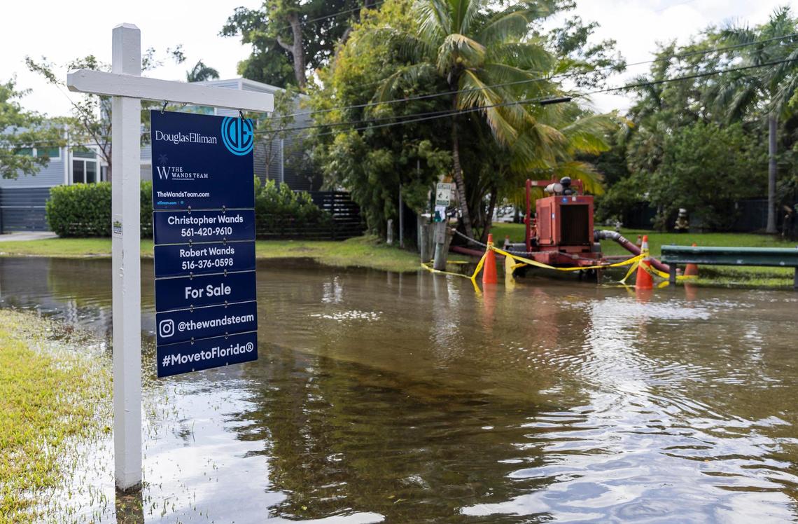 A for sale sign sticks out from a flooded street near a temporary pump at Miami’s Little River Pocket Park during a king tide in October 2023. As climate change makes flooding more frequent, home values may eventually suffer.