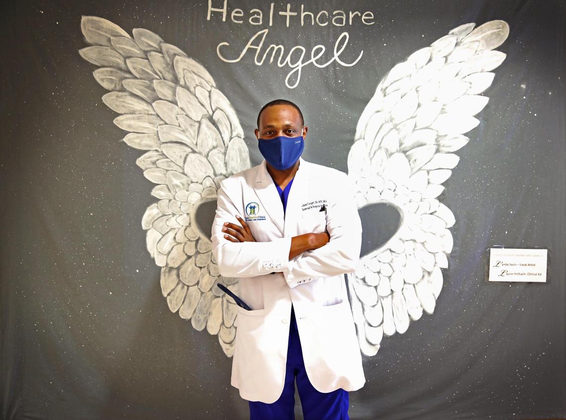 Sidney Coupet, a Doctor of Osteopathic Medicine, pictured in front of a ‘Healthcare Angels’ canvas by artist Lynda Sauls at Broward Health, in Fort Lauderdale, in between seeing patients. Coupet is leading the Haitian Task Force responding to COVID-19 which is hitting South Florida’s Haitian-American community especially hard.