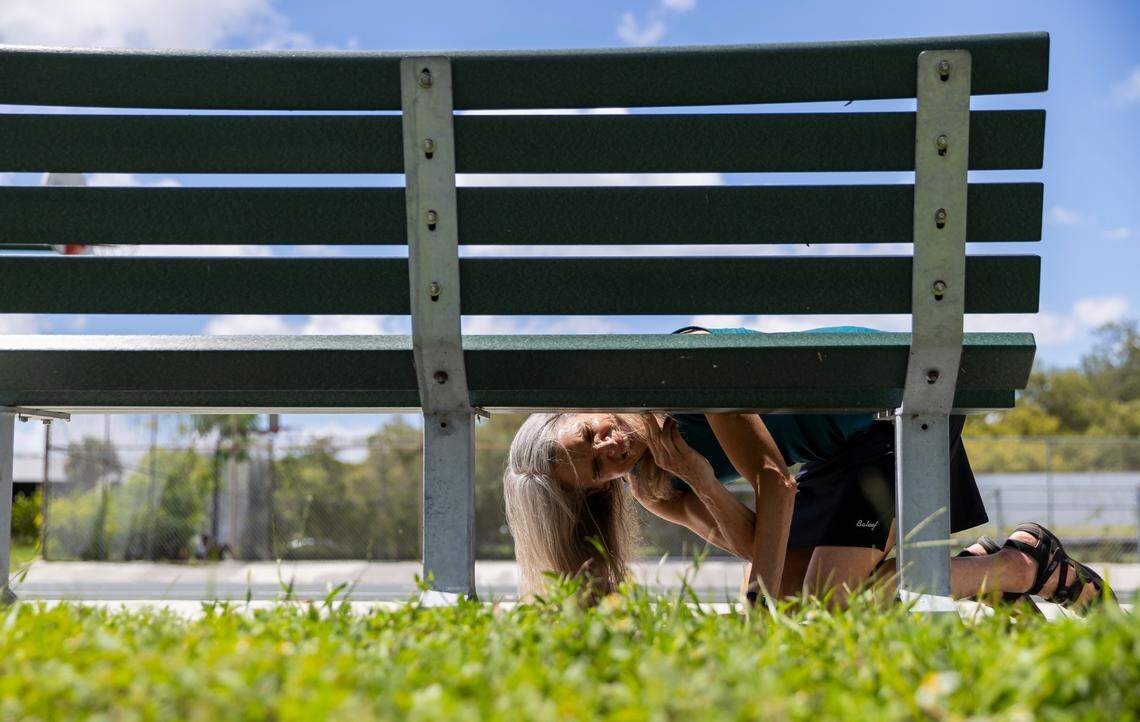 Jane Gilbert, Miami-Dade County’s chief heat officer, places a heat sensor underneath a bench at Eaton Park on Saturday, Sept. 10, 2022, in Miami, Fla. Gilbert participated in a citizen science event, Shading Dade, where volunteers were tasked with placing heat sensors in specific locations across Miami-Dade County to help record heat temperatures.