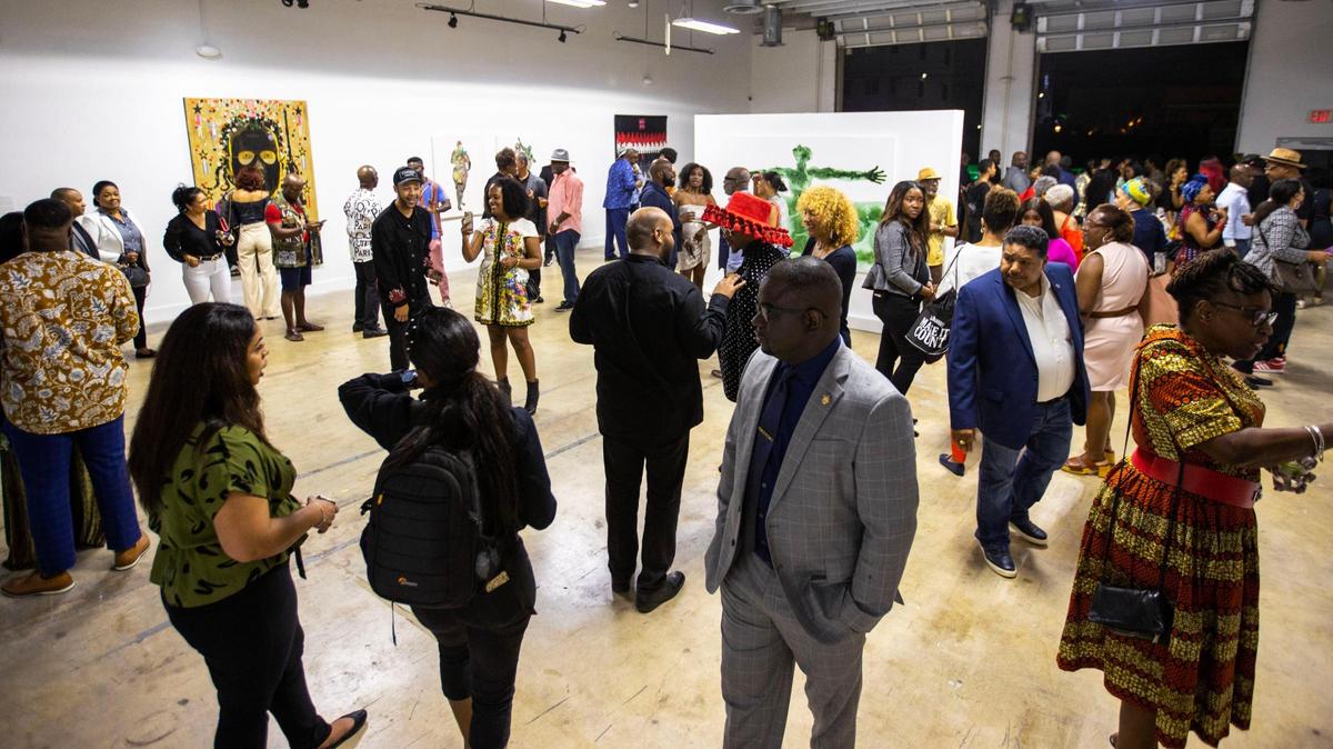 People socialize and view artwork during the Preview for The Art of Transformation event at The ARC and Logan Building in Opa-locka, Florida, on Wednesday, November 30, 2022.