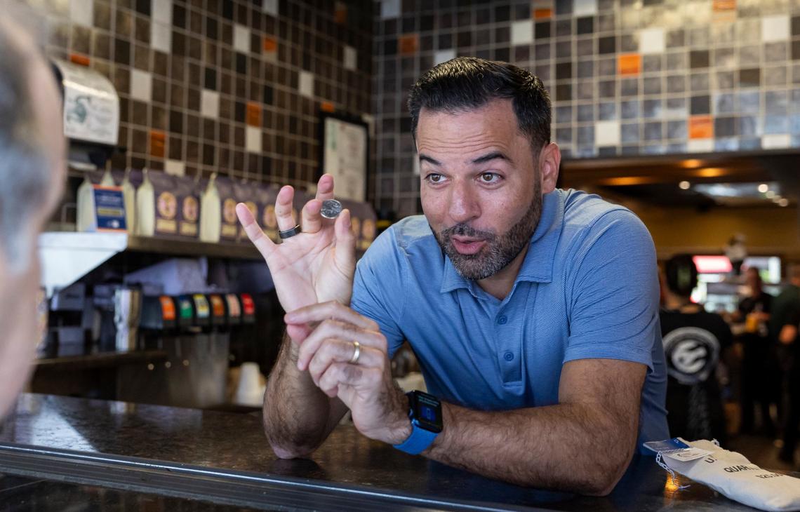 Latin Cafe 2000 owner Eric Castellanos shows off the Celia Cruz-themed quarter he is gifting customers.