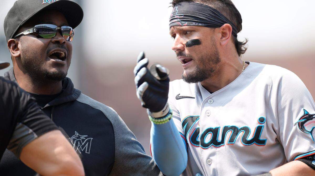 Miami Marlins bench coach James Rowson, left, holds back Miguel Rojas as he argues with first base umpire Mark Carlson after he ejected Rojas for arguing after being called out on strikes in the third inning of a baseball game against the Colorado Rockies Sunday, Aug. 8, 2021, in Denver. (AP Photo/David Zalubowski)