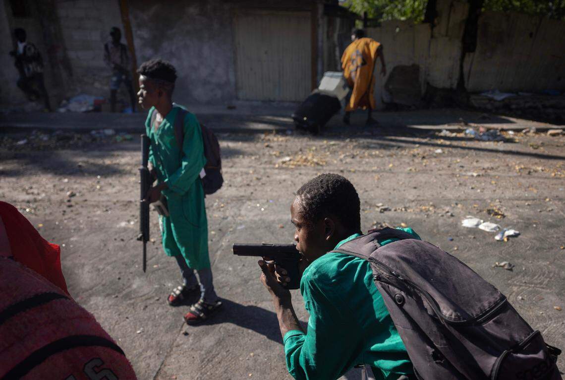Two nine-year-old boys guard a street during a raid in a neighborhood of Port-au-Prince on Dec. 7, 2024. The child in the foreground is aiming his pistol at the police.