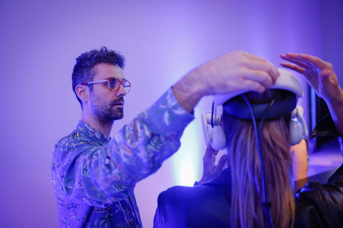 Mattia Casalegno, who was inspired to create “Aerobanquets RMX” by a 1932 futuristic cookbook, helps a guest with her VR headset.