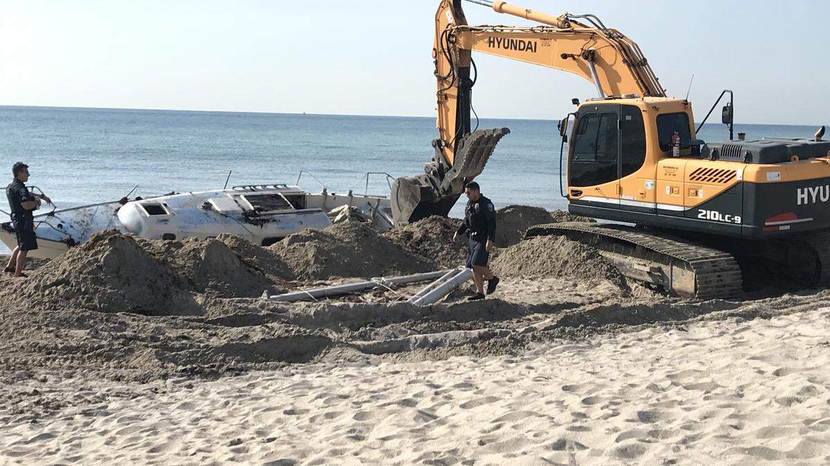 The sailboat is wrested from the sand Thursday morning by crane.