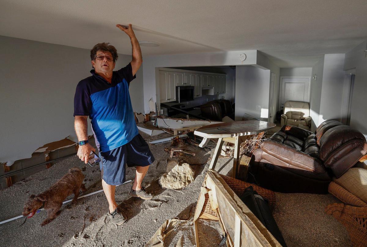 Adam Robinson se encuentra sobre una pila de arena de playa dentro de su casa causada por la marejada ciclónica de los huracanes Helene y Milton en el condominio frente a la playa Fisherman’s Cove en Siesta Key, Florida, el jueves 10 de octubre de 2024.