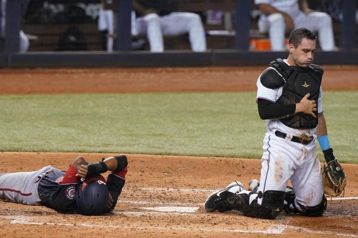 Washington Nationals’ Alcides Escobar and Miami Marlins catcher Nick Fortes take their time getting up after colliding at home plate in the sixth inning of a baseball game, Tuesday, Sept. 21, 2021, in Miami. Escobar scored on the play. (AP Photo/Marta Lavandier)