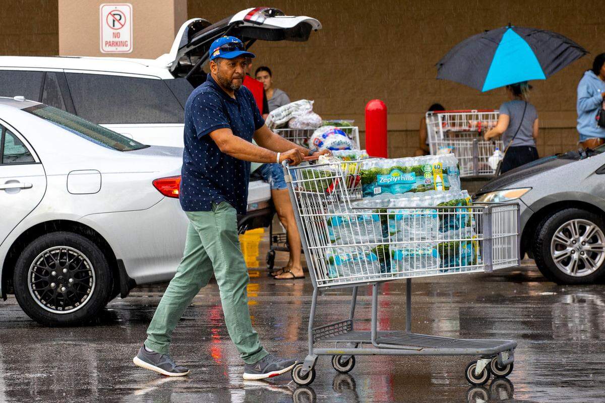 In this 2022 file photo, JeLuis Ortuno, 44, walks a cart full of water to his car as he prepares for potential landfall by Hurricane Ian at Costco in Miami, Florida, on Saturday, September 25, 2022.
