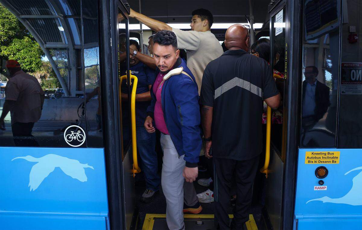 Metro Express commuter Gabriel Moreno, 37, center, exits the crowded bus in favor of empty bus as he makes his way to work on the first day of Miami-Dade's $300 million rapid-transit bus line known as “Metro Express” on Monday, October 27, 2025, just west of Richmond Heights on Coral Reef Drive and U.S. 1.  Many first day riders complained about crowded buses and long travel times due to red lights on the express lane.